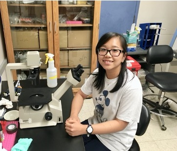 Linh Vo using a microscope