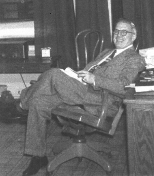 Photo of George A. Kopp leaning back in chair.