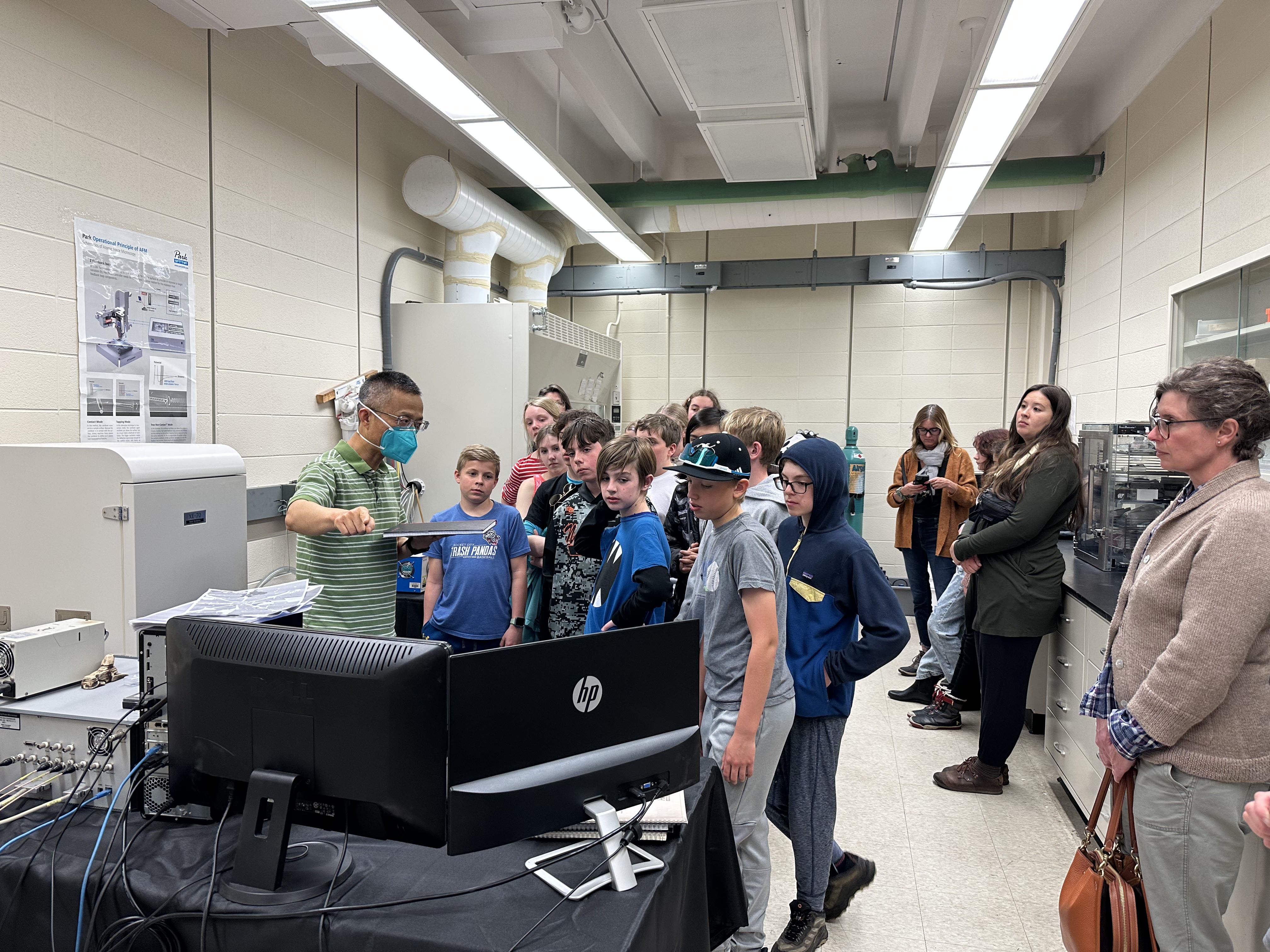 Prof. Zhou in his lab, talking to sixth-grade students